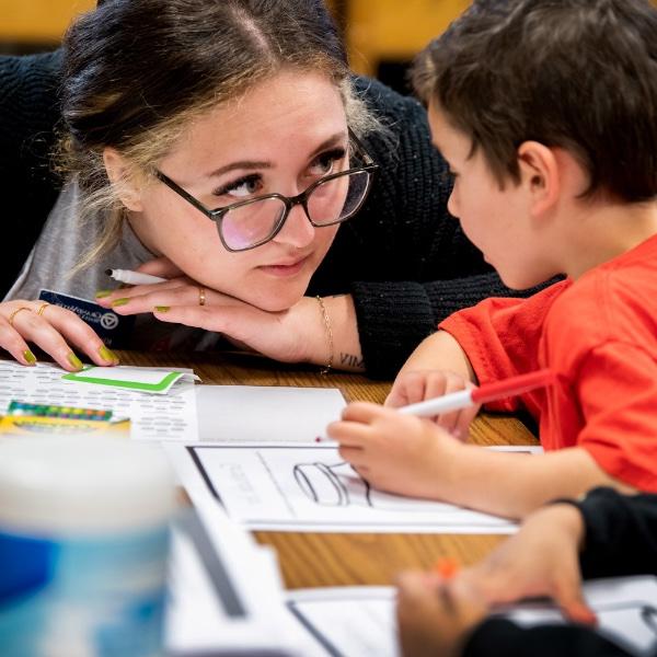 A Grand Valley Master of Public Health student works with a student who is drawing.